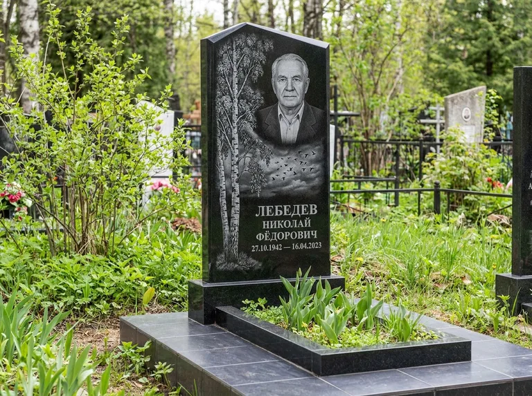 Памятник с гравировкой берёзы: вертикальная стела со скошенным верхом — берёза и стая птиц в небе, гранитный цоколь с тёмной плиткой, работа «Лебедев» в Уфе