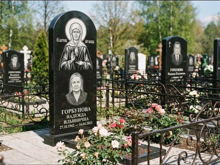Памятник с гравировкой иконы: стела с арочным верхом и киотом под образ — гравировка образа Матроны Московской, гранитный цоколь с тёмной плиткой, работа «Ковалёв» в Уфе