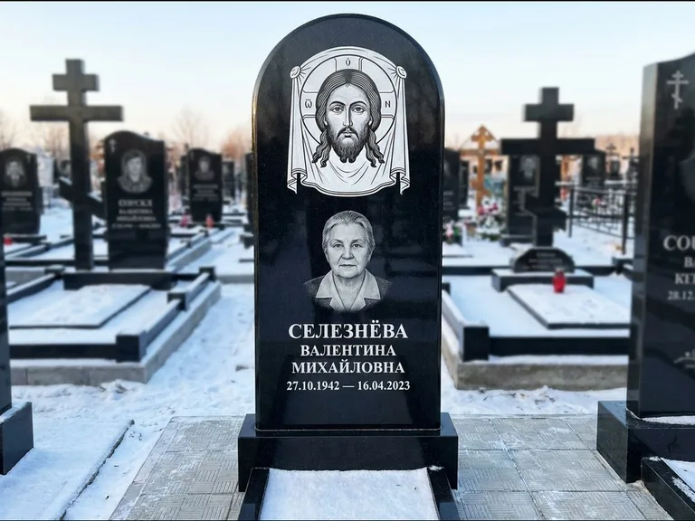 Памятник с гравировкой иконы: небольшая скромная одиночная стела с именной иконой — золочёный нимб на образе, аккуратный участок с газоном, работа «Ковалёв» в Уфе