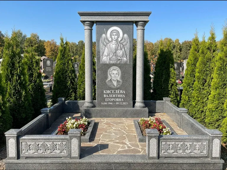 Памятник с гравировкой иконы: массивная стела с двускатным навершием-домиком — гравировка Николая Чудотворца, живая изгородь из туи, работа «Журавлёв» в Уфе