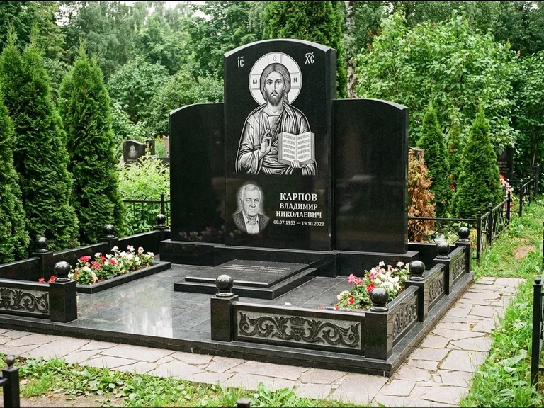 Памятник с гравировкой иконы: широкая панорамная стела с золочёным нимбом — гравировка образа Матроны Московской, цветник с белыми хризантемами, работа «Мельникова» в Уфе