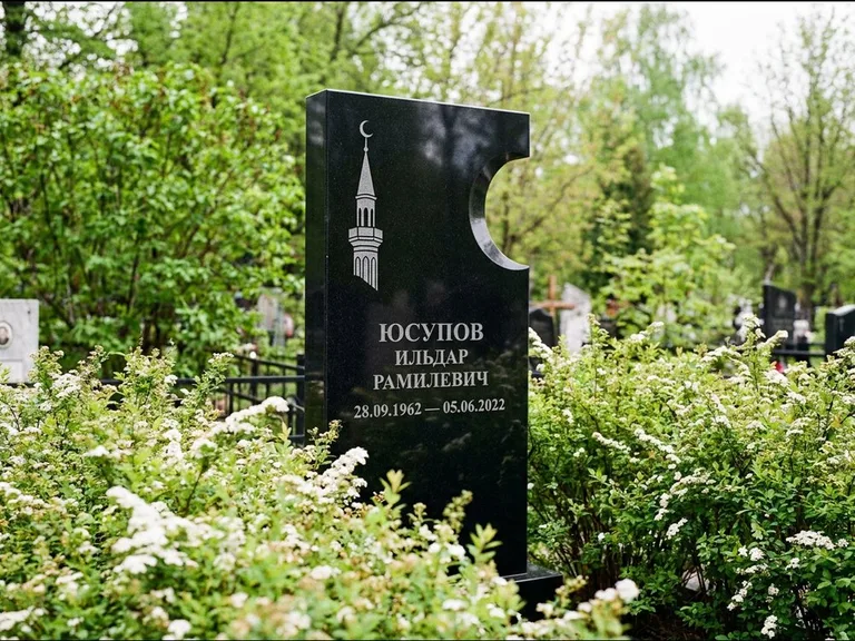 Мусульманский памятник с гравировкой мечети: стела с боковым вырезом в форме полумесяца — гравировка минарета с полумесяцем, низкие кусты спиреи в цвету, работа «Юсупов» в Уфе