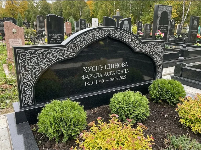 Мусульманский памятник: вытянутая горизонтальная семейная стела с аркой — белая гравировка силуэта мечети с минаретами, участок с декоративными кустами, работа «Зарипова» в Уфе