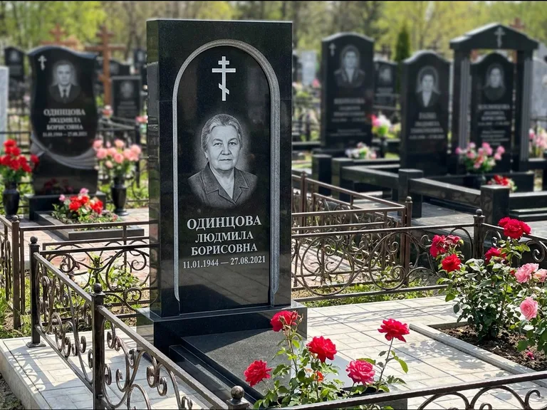 Памятник из чёрного гранита — скромная невысокая стела с крестом с терновым венцом, работа «Лаврентьева» в Уфе