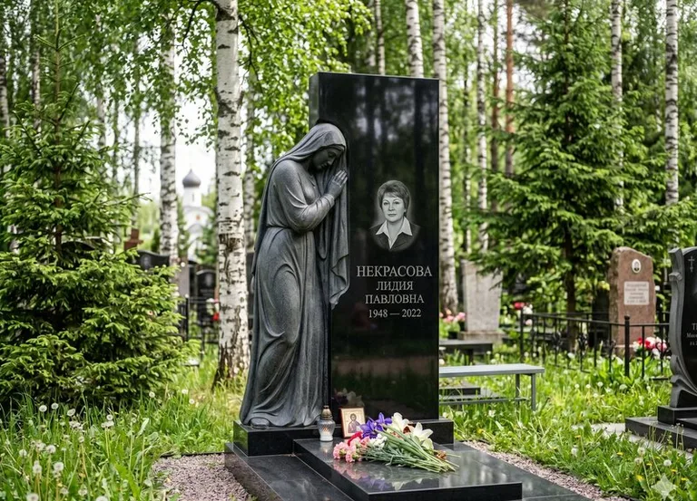 Гранитная фигура скорбящего мужчины у чёрной стелы в Уфе